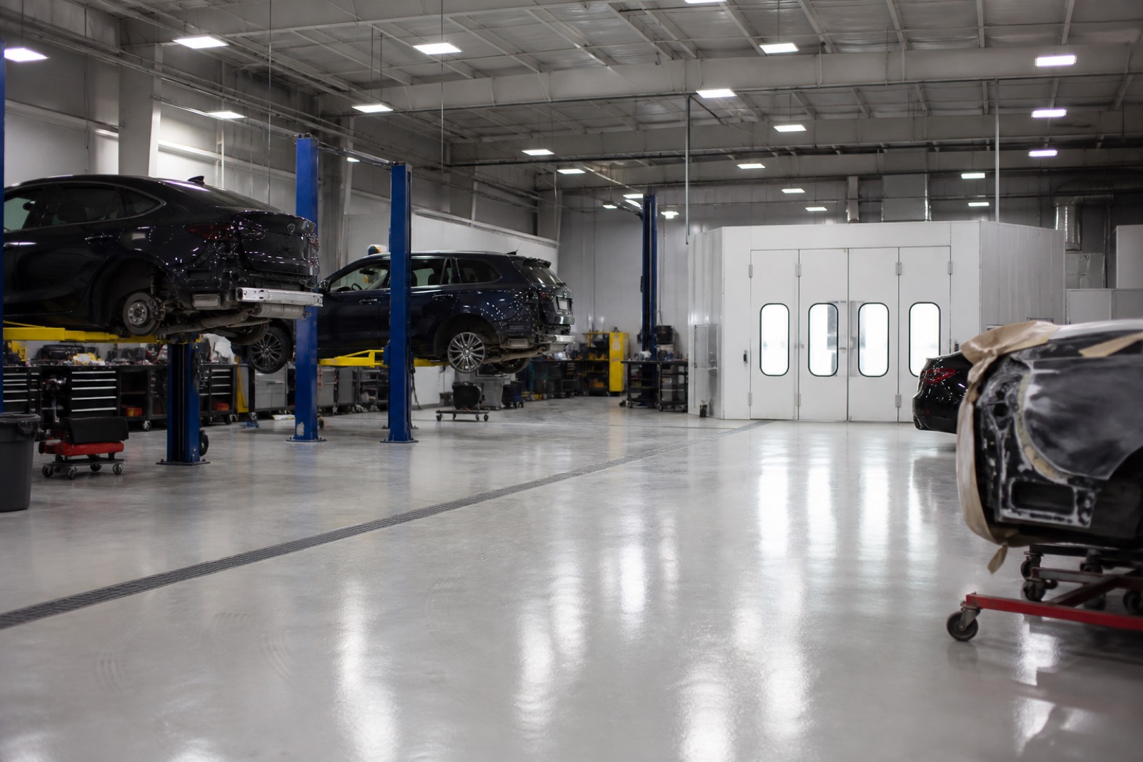 Clean auto body shop interior with cars on lifts and a paint booth