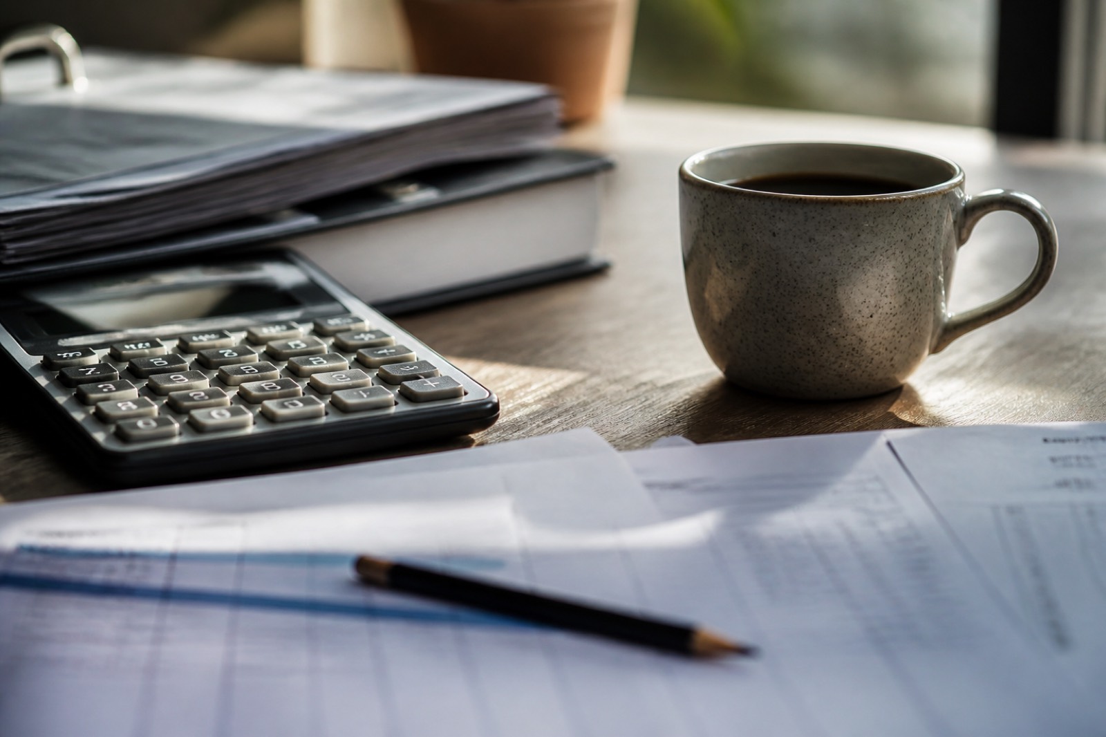 Calculator, pencil and ledger pages used to calculate EBITDA margin