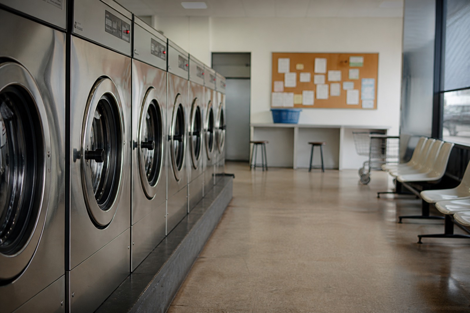 Washers and bulletin board in a laundromat whose owner may sell, finding a laundromat for sale