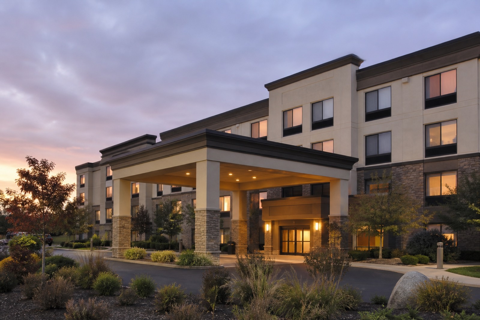 Suburban hotel exterior with a covered entrance at dusk
