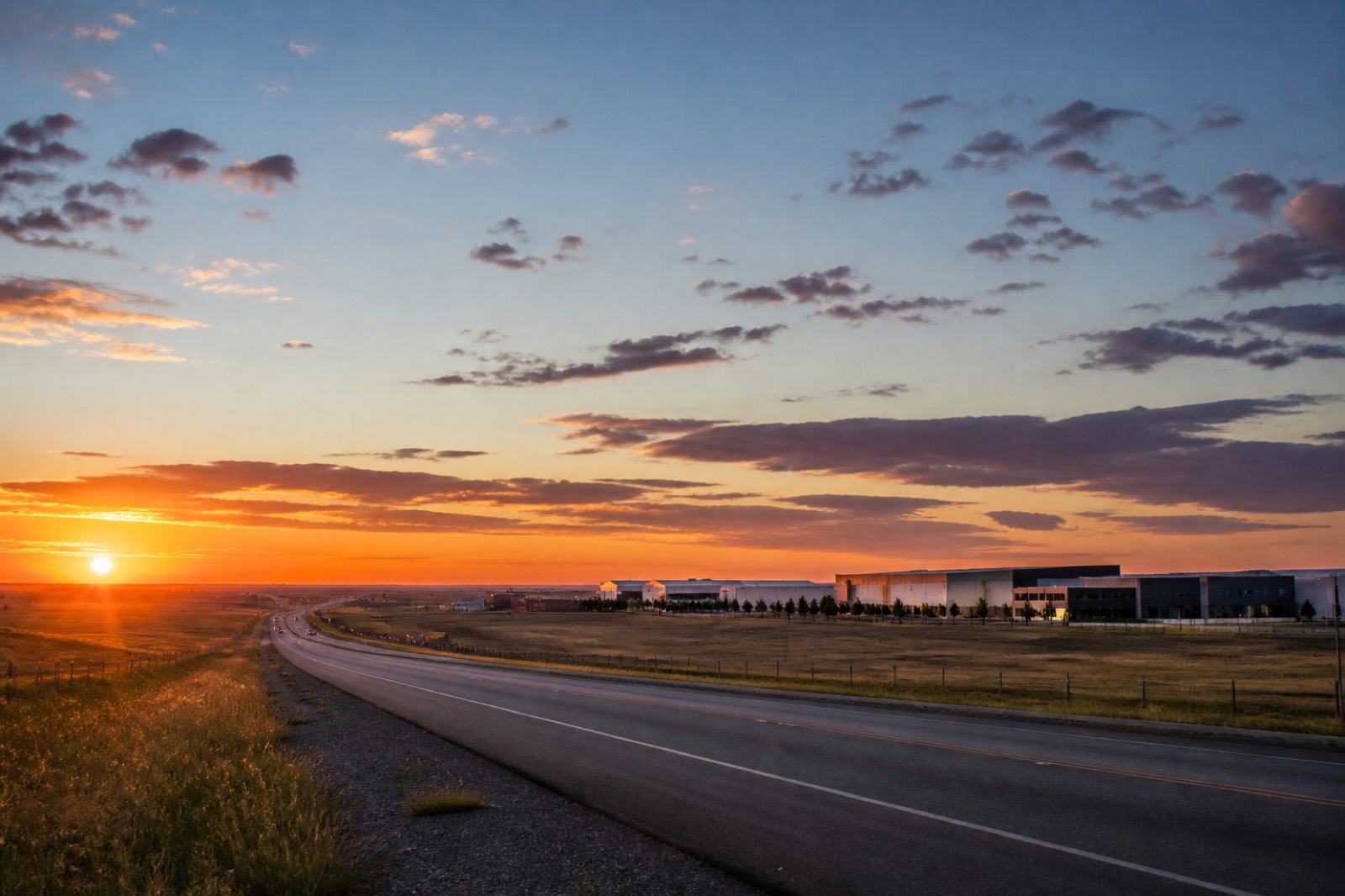 Highway leading to a business park across flat land at sunset