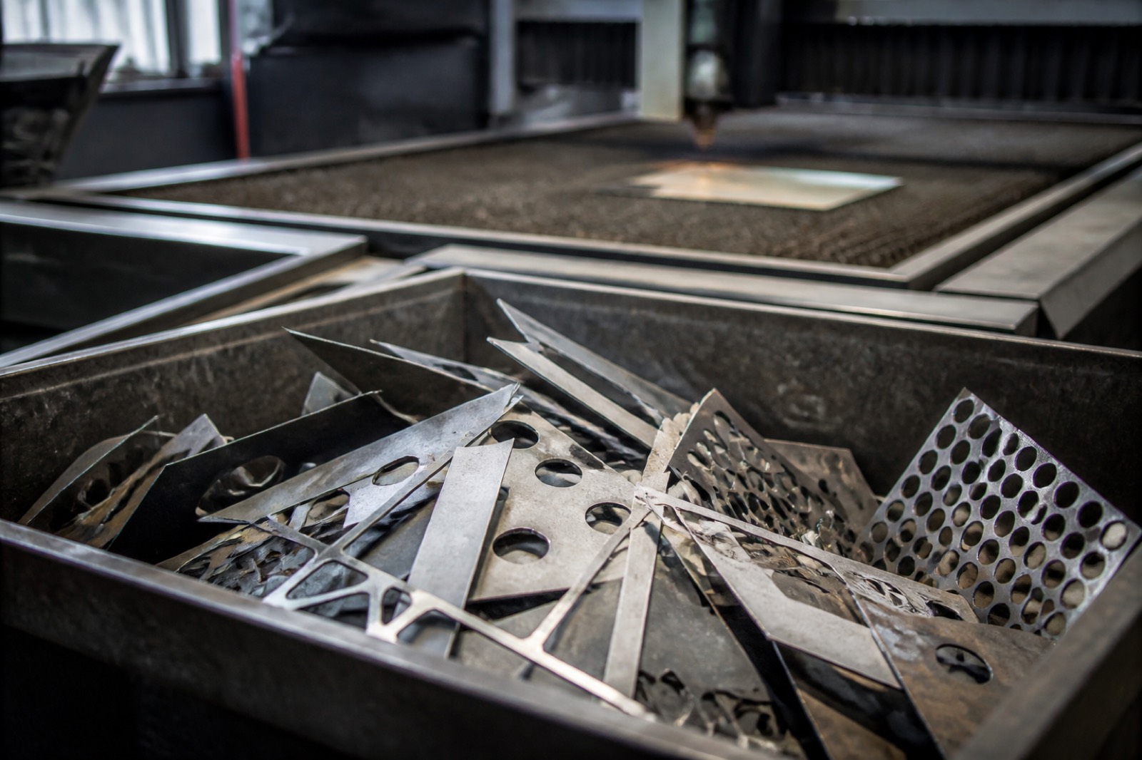 Scrap bin of steel offcuts beside cutting equipment in a metal fabrication business
