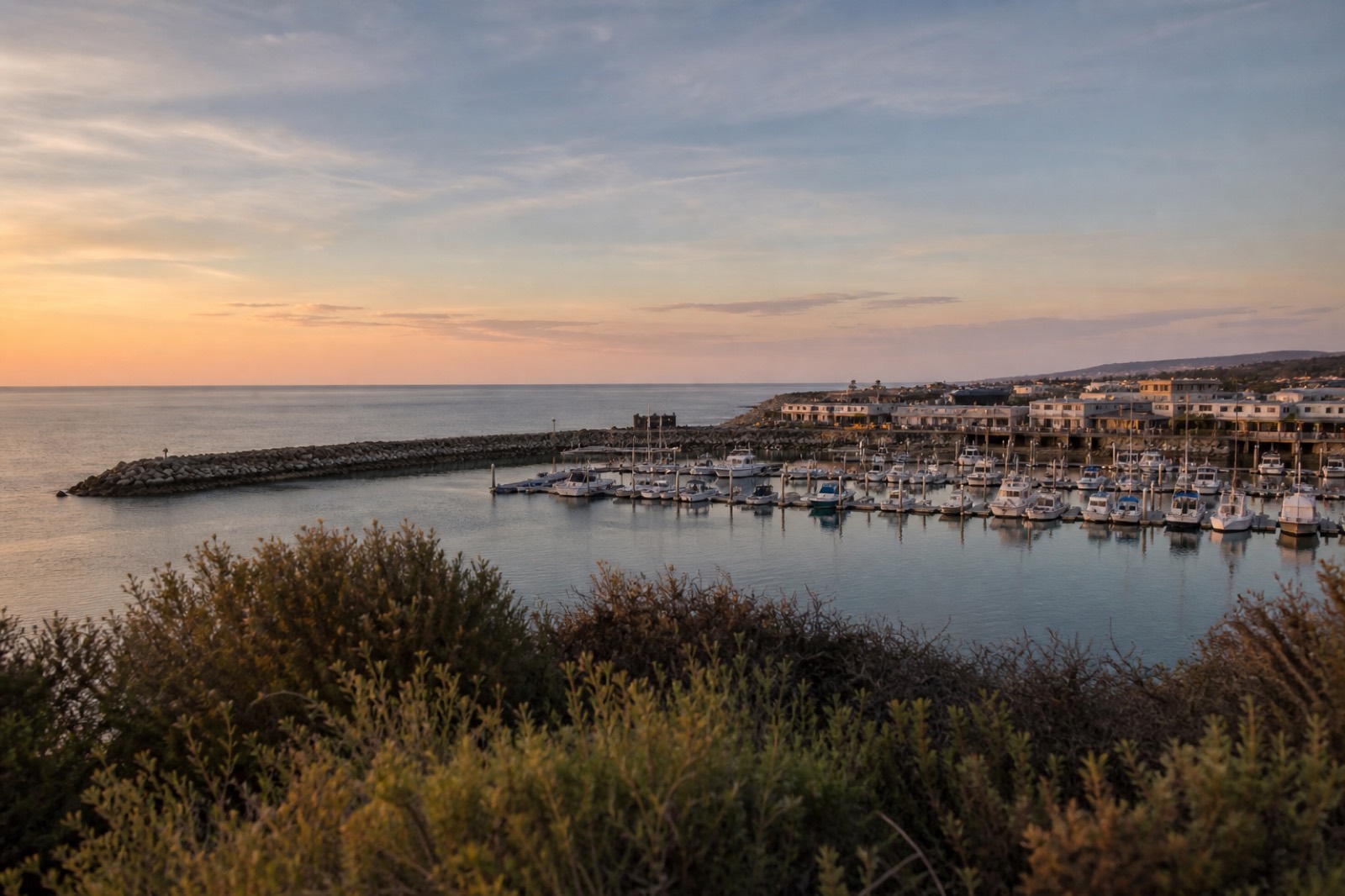 Coastal view of a marina and low rise commercial buildings at sunrise